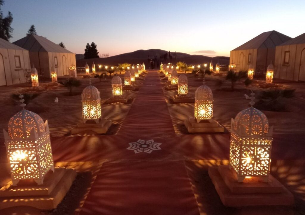 Luxury desert camp lanterns walkway dusk, Morocco