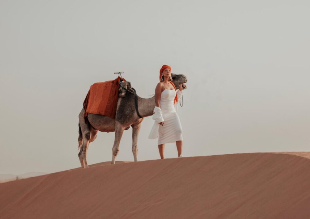 Woman camel dune photoshoot sunset, Morocco